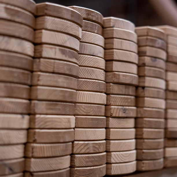 Nahaufnahme von gestapelten Thermoholz-Profilen, die die abgerundeten Kanten und die Jahresringe des Holzes zeigen.